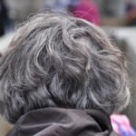 The back of an older person's grey head in a crowd